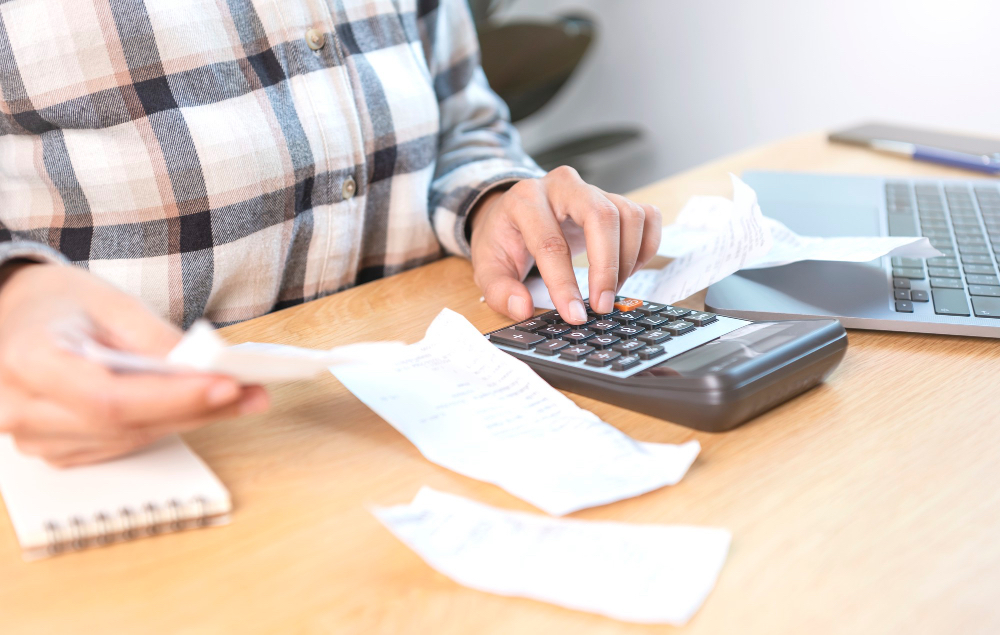 business-woman-pressing-calculator-calculate-various-costs-that-must-be-paid-by-bill-invoices-held-placed-table